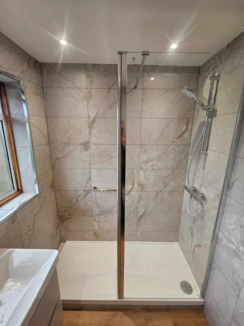 Walk-in shower with marble-effect walls and chrome fittings